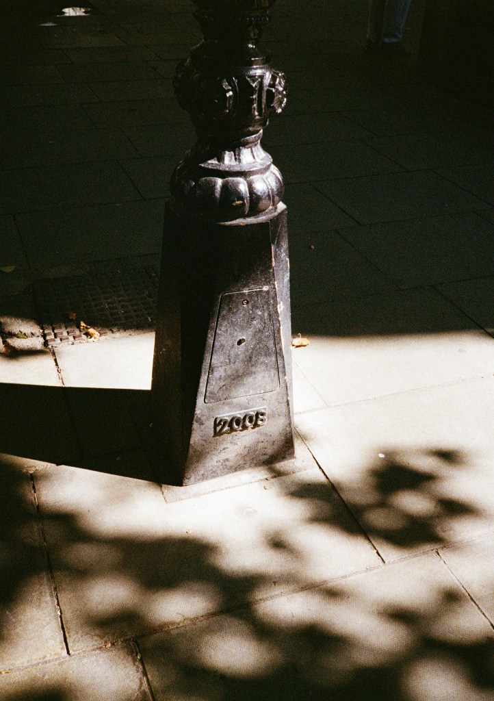 photo of lamppost base with sun and shadow around it