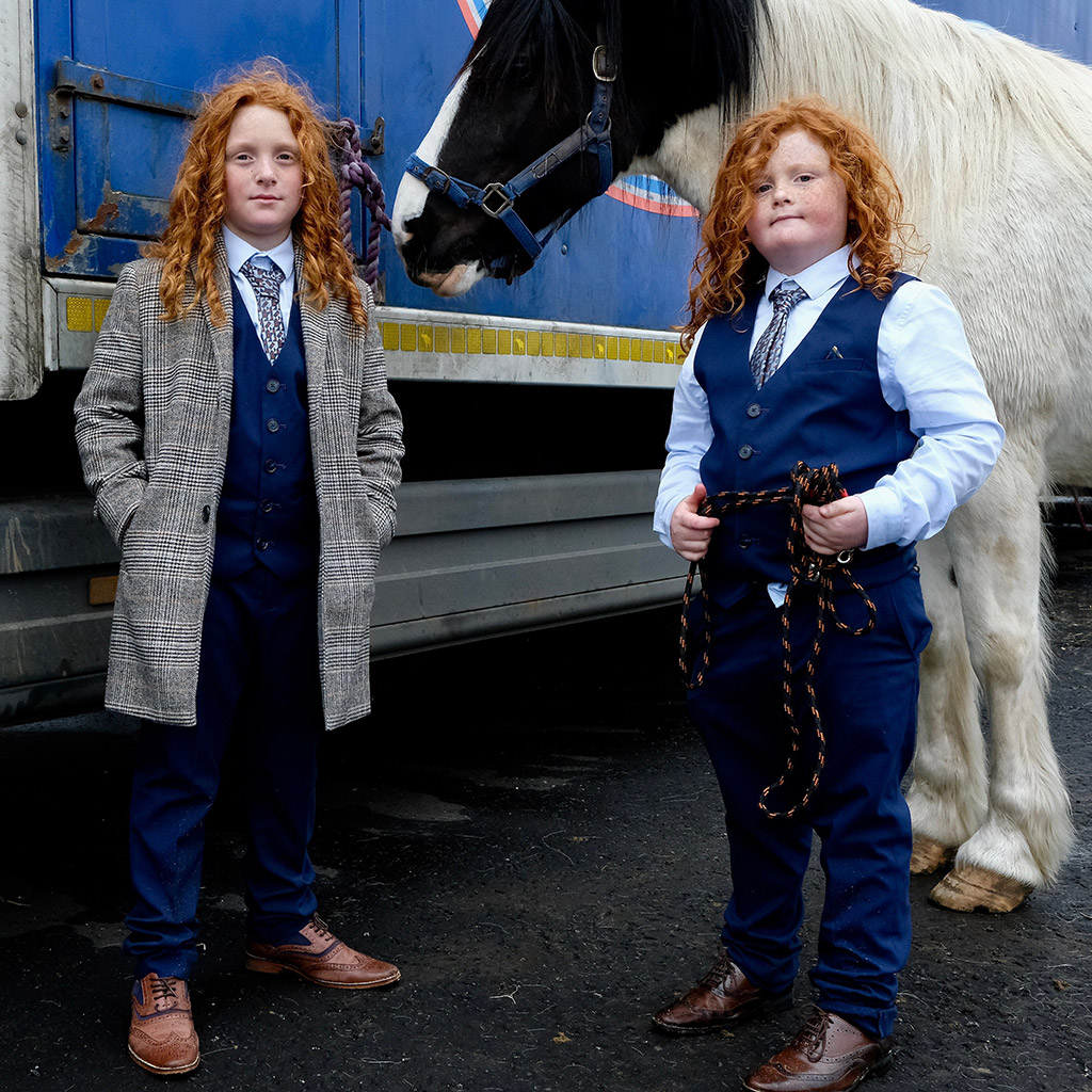 twin boy with flame-red curls, placed so well against the blue backdrop. Not only are they dressed like adults, but also there is a maturity and assuredness about them winner people round apoy