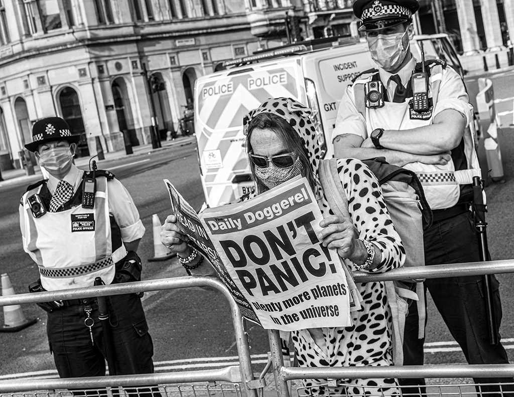 woman reading newspaper that says "don't panic" in big letters on the front