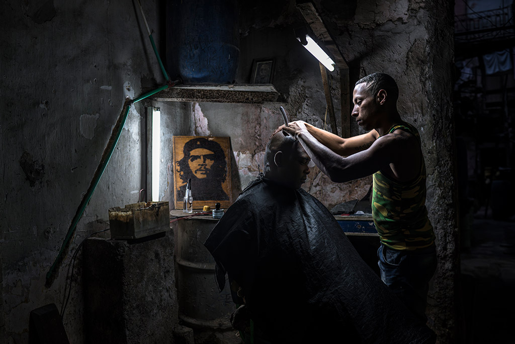 dark dingy room with two people one a barber and the other the client having their hair done people apoy 2024