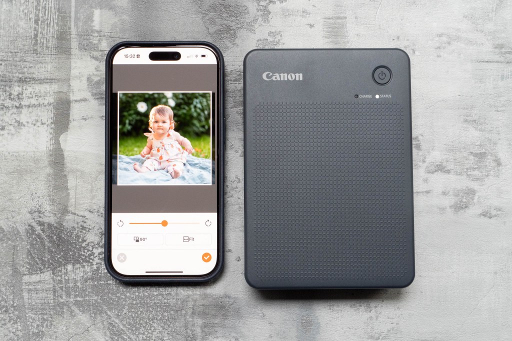 The Selphy QX20 next to an iPhone showing the Selphy Photo Layout app. Image: Amy Davies