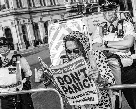 woman reading newspaper that says "don't panic" in big letters on the front