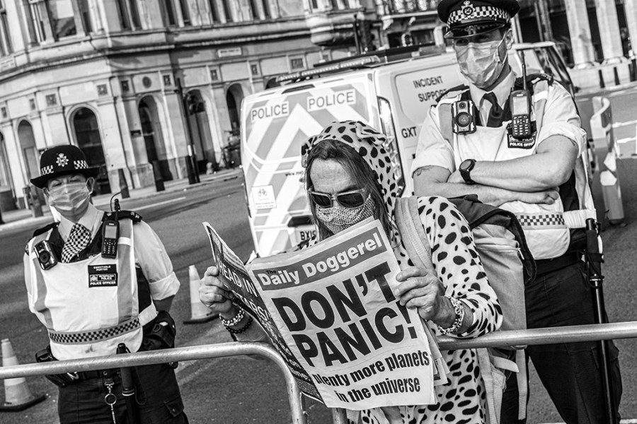 woman reading newspaper that says "don't panic" in big letters on the front