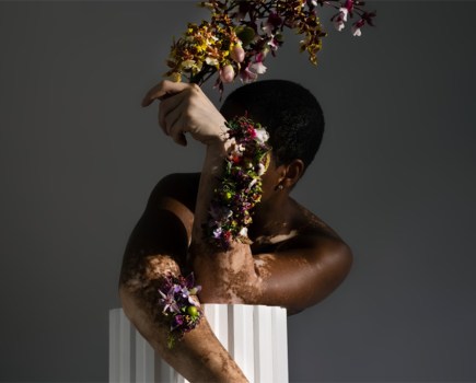 portrait of person with golden foliage prop in front of face