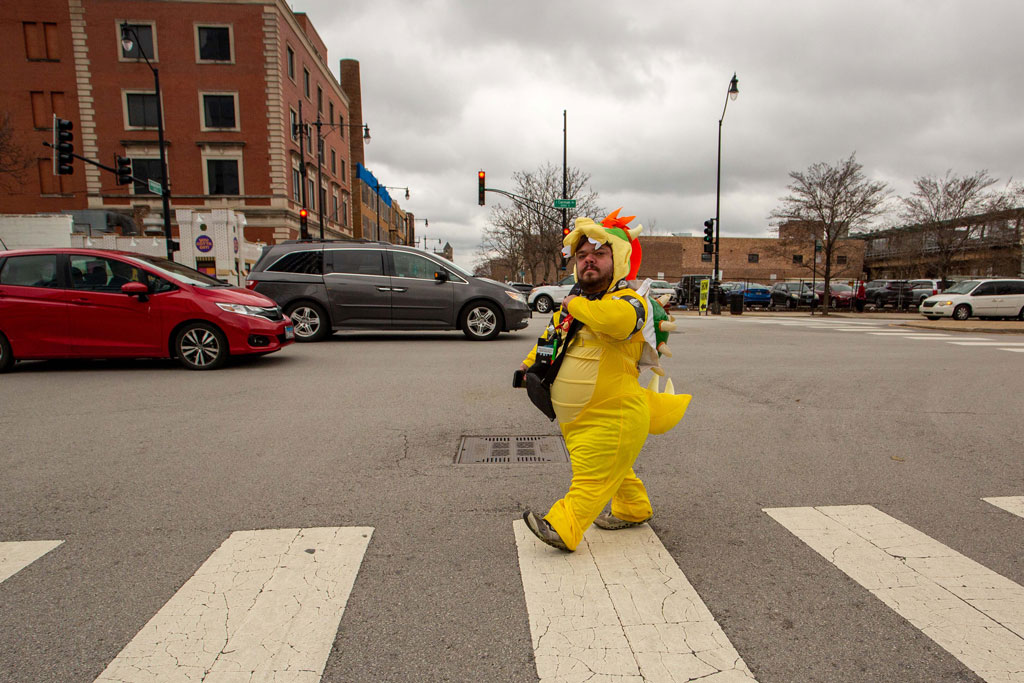 Chicago a little person dressed as a yellow dragon walks on zebra crossing