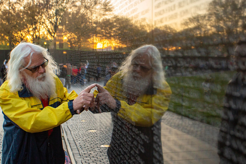 Washington Vietnam War memorial an old man point at a name on the wall