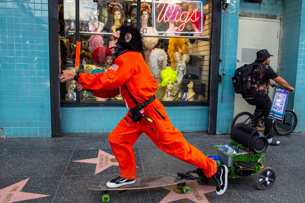 Los Angeles a person dressed as a monkey in an orange astronaut overall skateboards on the Walk of Fame