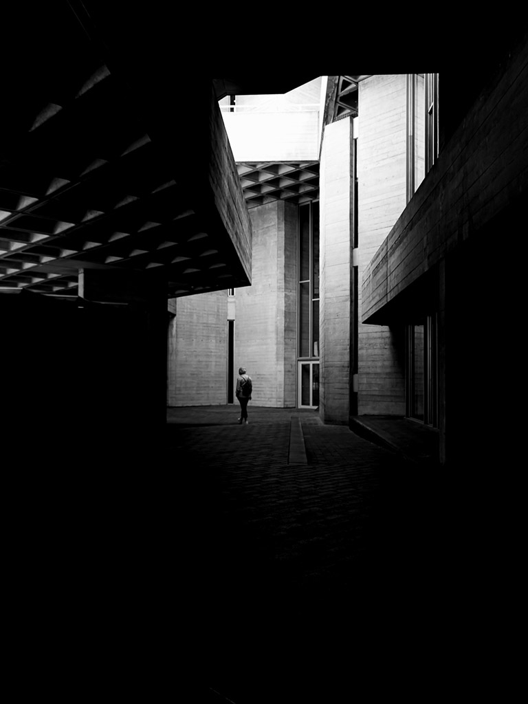 one person walking amongst shadow of buildings