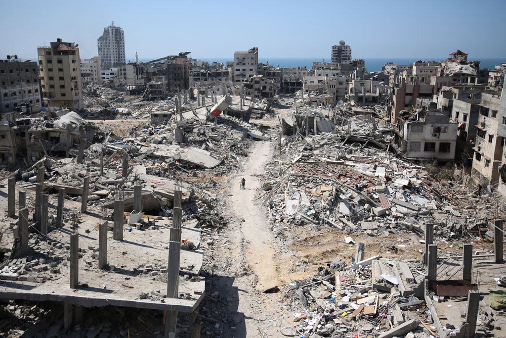 A man pushes a bycicle along as he walks amid building rubble in the devastated area around Gaza's Al-Shifa hospital on April 3, 2024, amid the ongoing conflict between Israel and the Palestinian Hamas militant group.