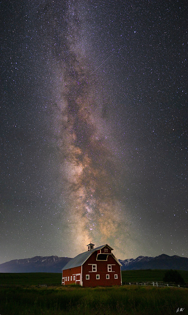 astronomy photo of milky way stars over a house in the landscape