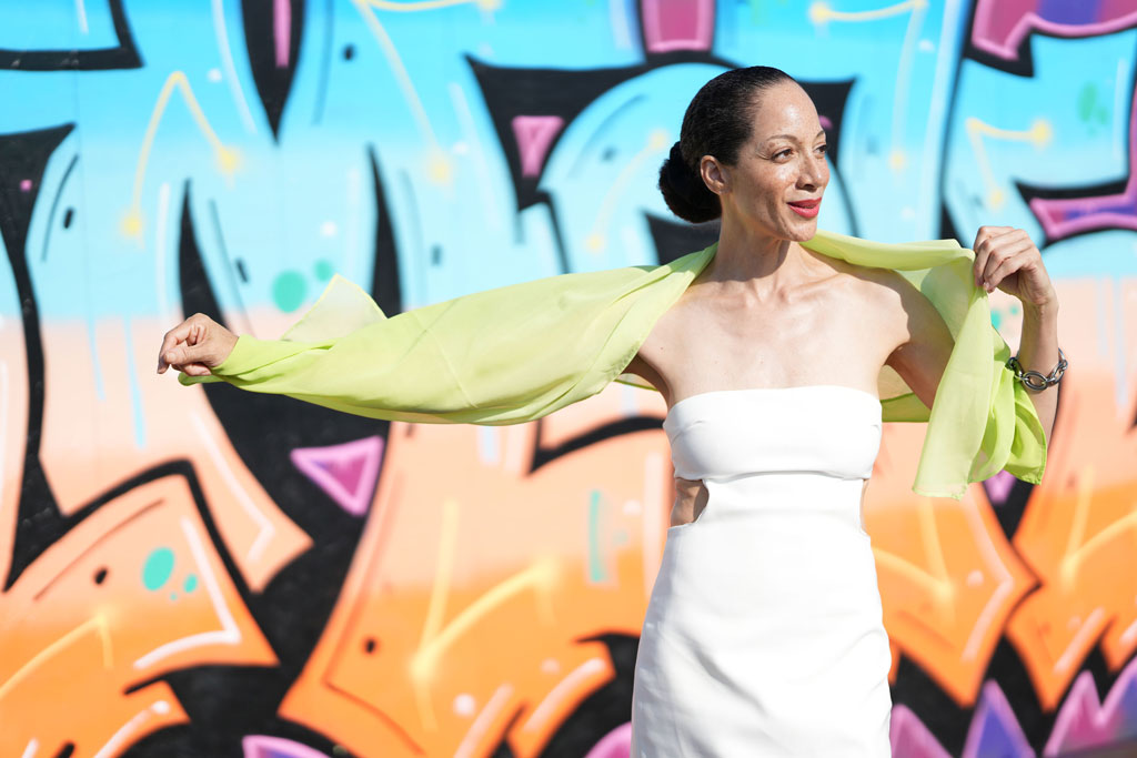 Sony FE 85mm F1.4 GM II sample image portrait of a woman in a white dress in front of a colourful graffiti wall