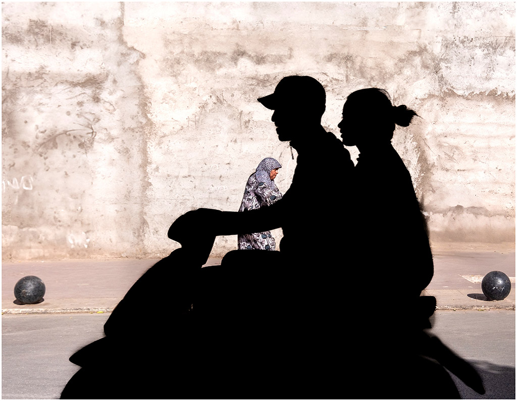 silhouette of two people on a moped