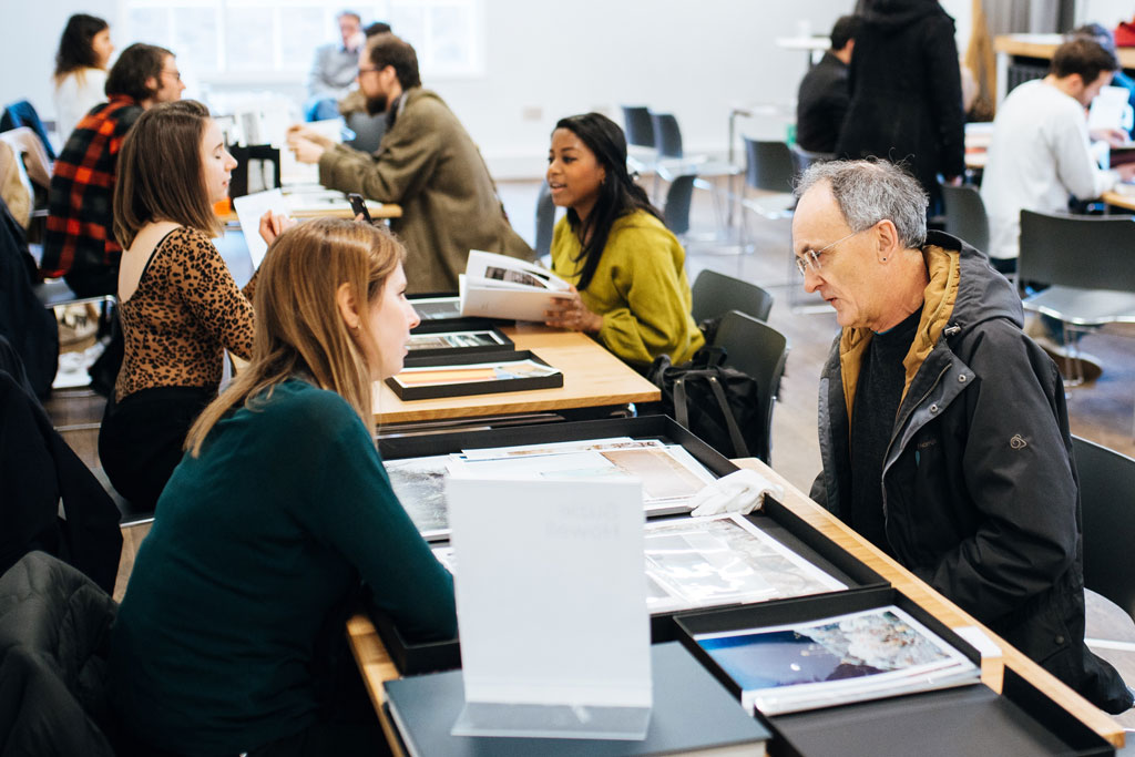 People sitting at desks discussing photography portfolios