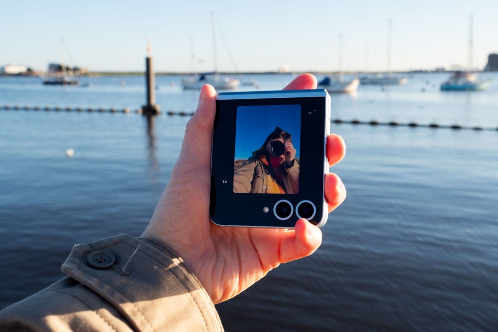 Samsung Galaxy Z Flip 6 in hand, folded to show the front screen taking a selfie