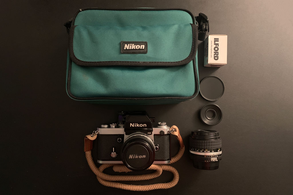 Nikon F2AS flat lay with camera bag, extra lens and film