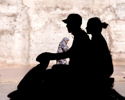 silhouette of two people on a moped