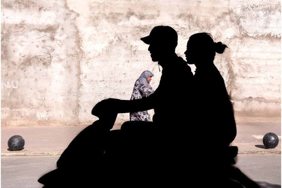 silhouette of two people on a moped