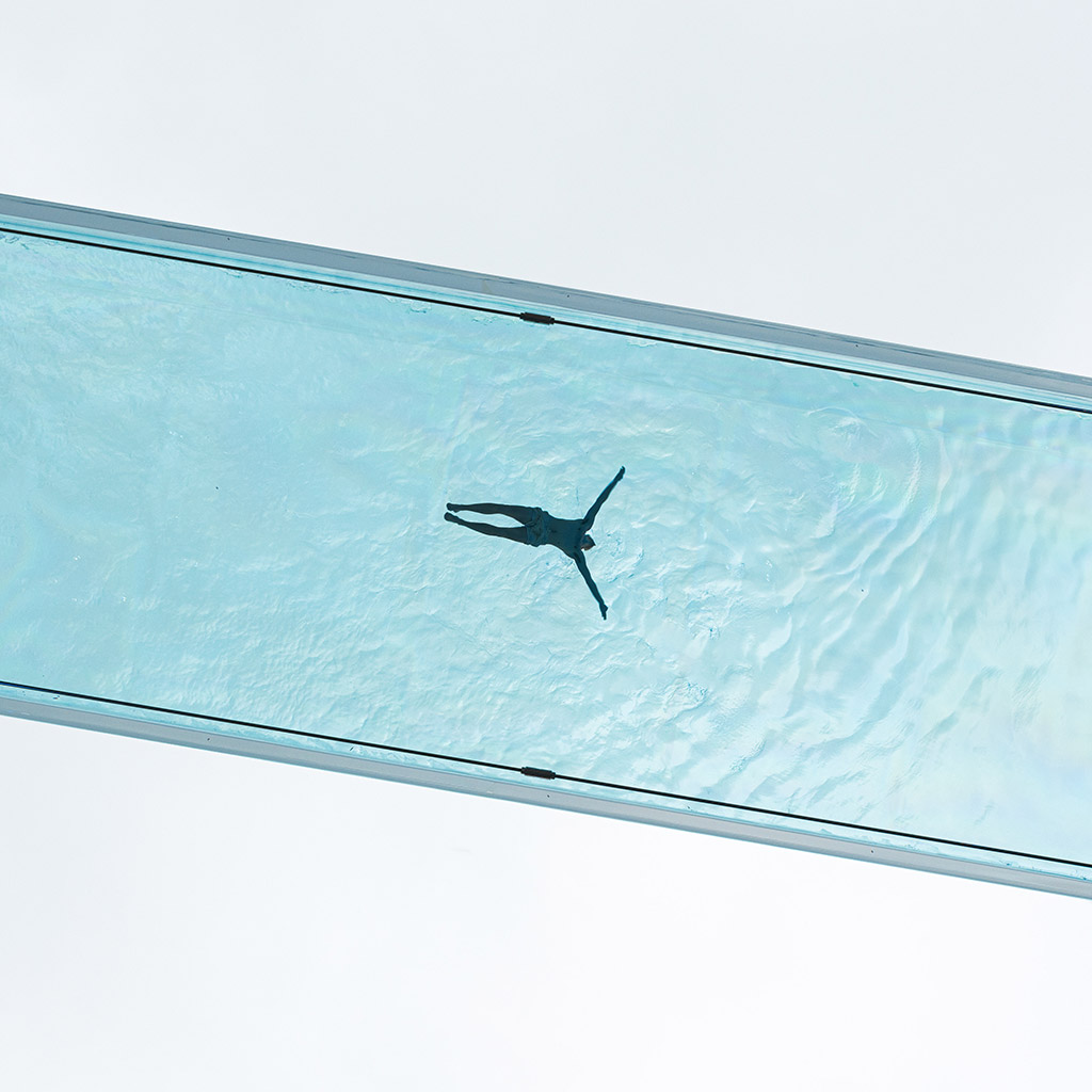 minimalist photo looking up at a swimming pool clear bottom swimmer in the middle