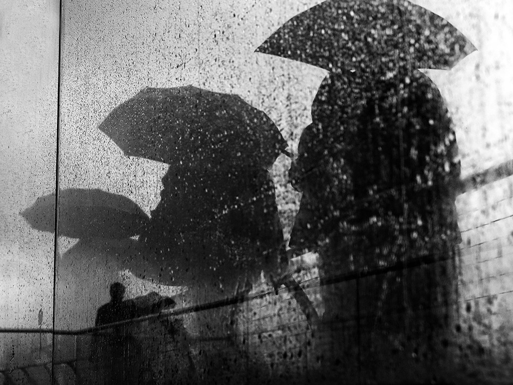 street photo with three people in the rain with umbrellas silhouettes