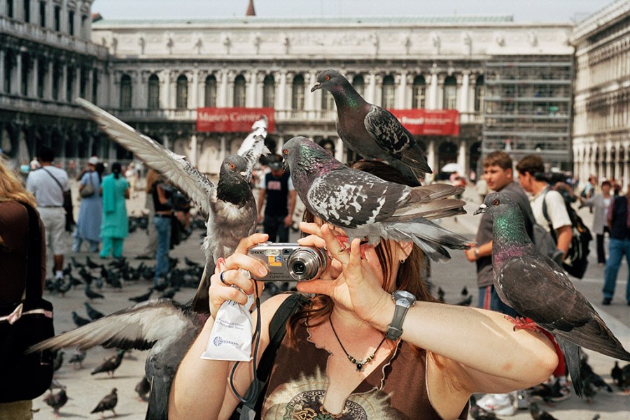 Venice, Italy, 2005 © Martin Parr / Magnum Photos woman holding up compact camera with pigeons on shoulder