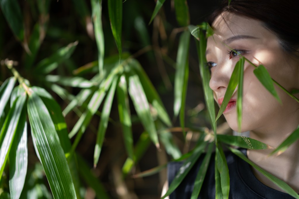 portrait of a woman with bamboo leaves around her face, shot with the Zeiss Otus ML 85mm F1.4 lens