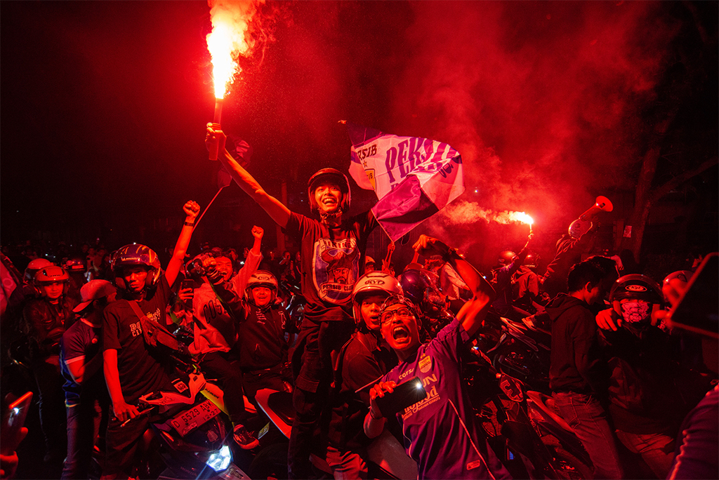elation of fans celebrating a win by their local football club by lighting flares in Bandung, West Java