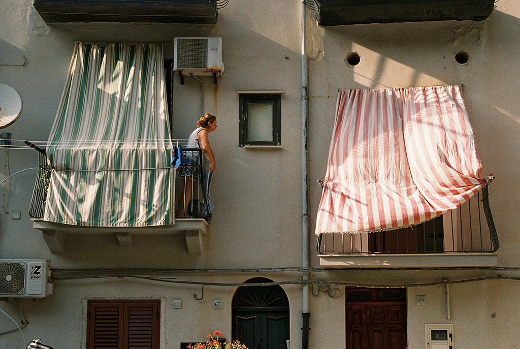 film photo in italy person duting off balcony