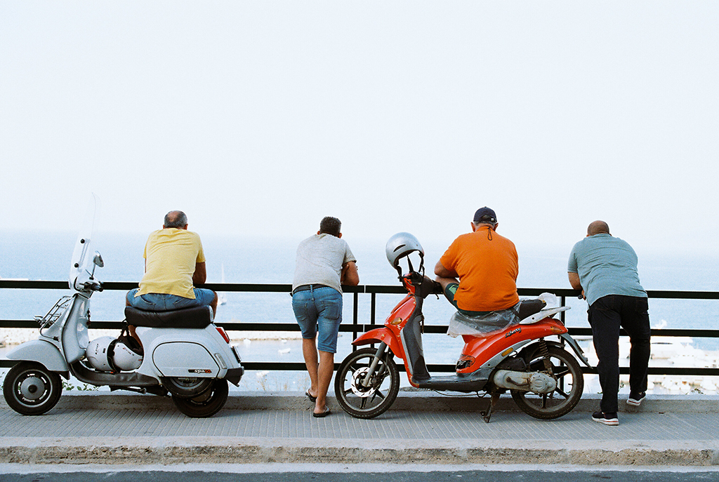 film photo in italy men on mopeds watching something