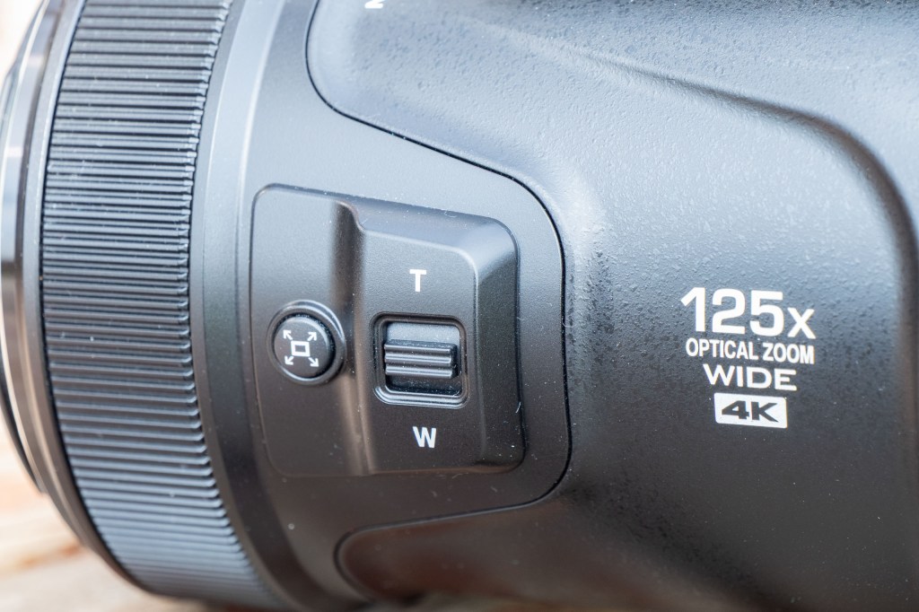 Two of the buttons on the side of the Nikon P1100's lens