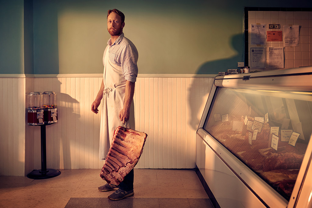 butcher holding large piece of meat