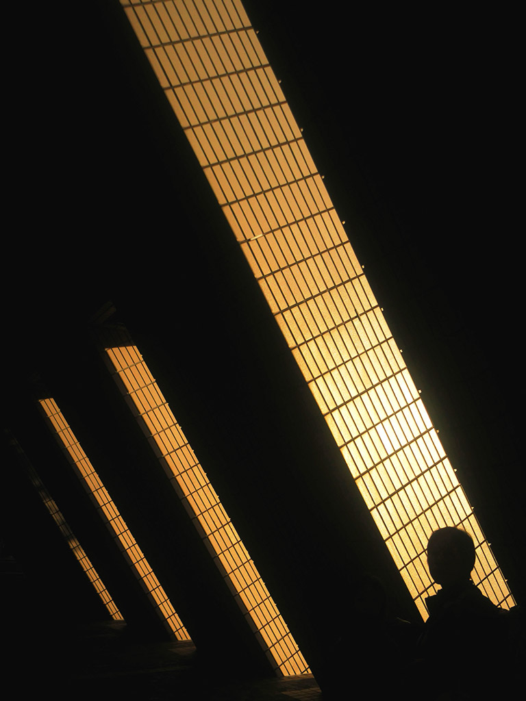 street photo with lines of golden light amongst the shadows
