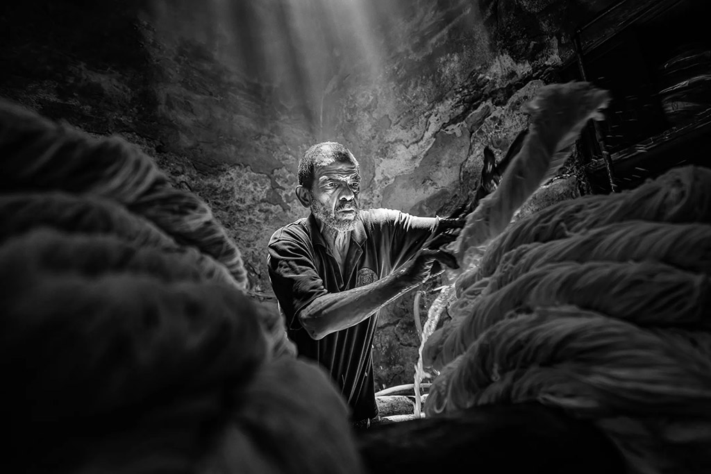 Man cleaning piles of fabric