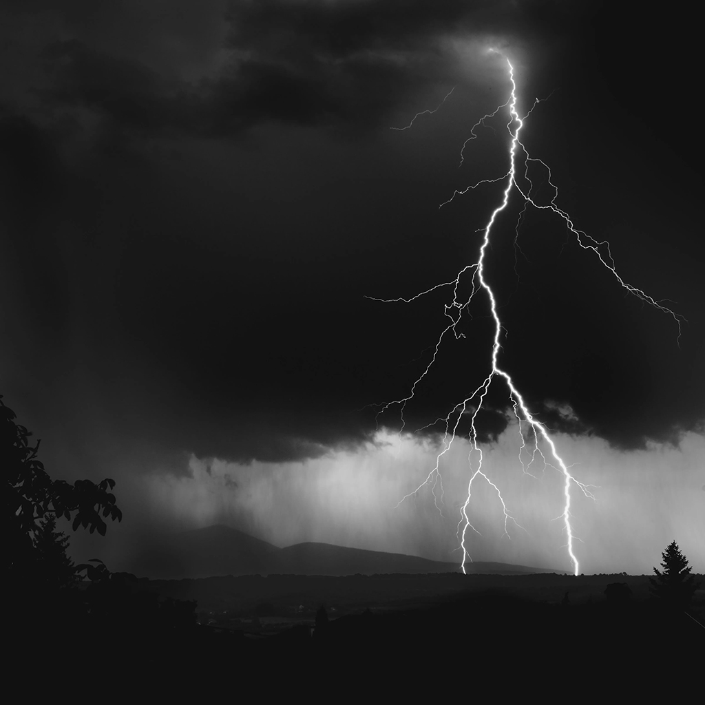 landscape photograph in black and white of a lightning bolt hitting the hills