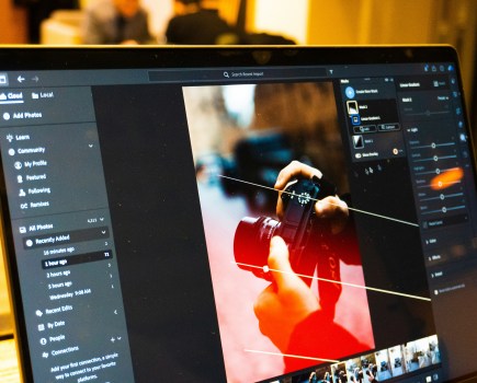 Photograph of laptop with photo editing software open being used to edit a photograph of hands holding a camera.