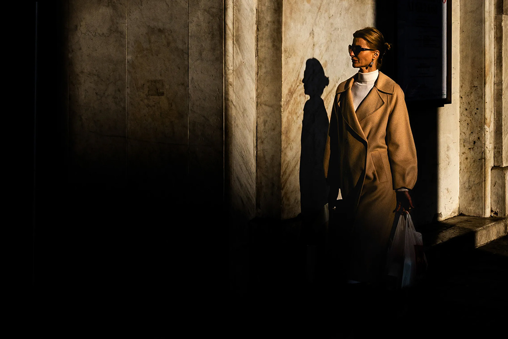 woman on the street walking into shadows from a patch of light
