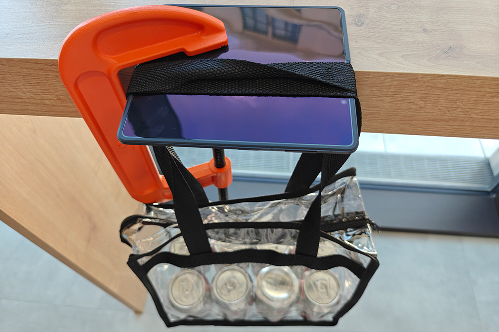 The hinge on the Honor Magic V5 has been upgraded to what Honor has called a Super Steel Hinge. Tested here with a clamp and bag containing six cans pulling on the phone's hinge.