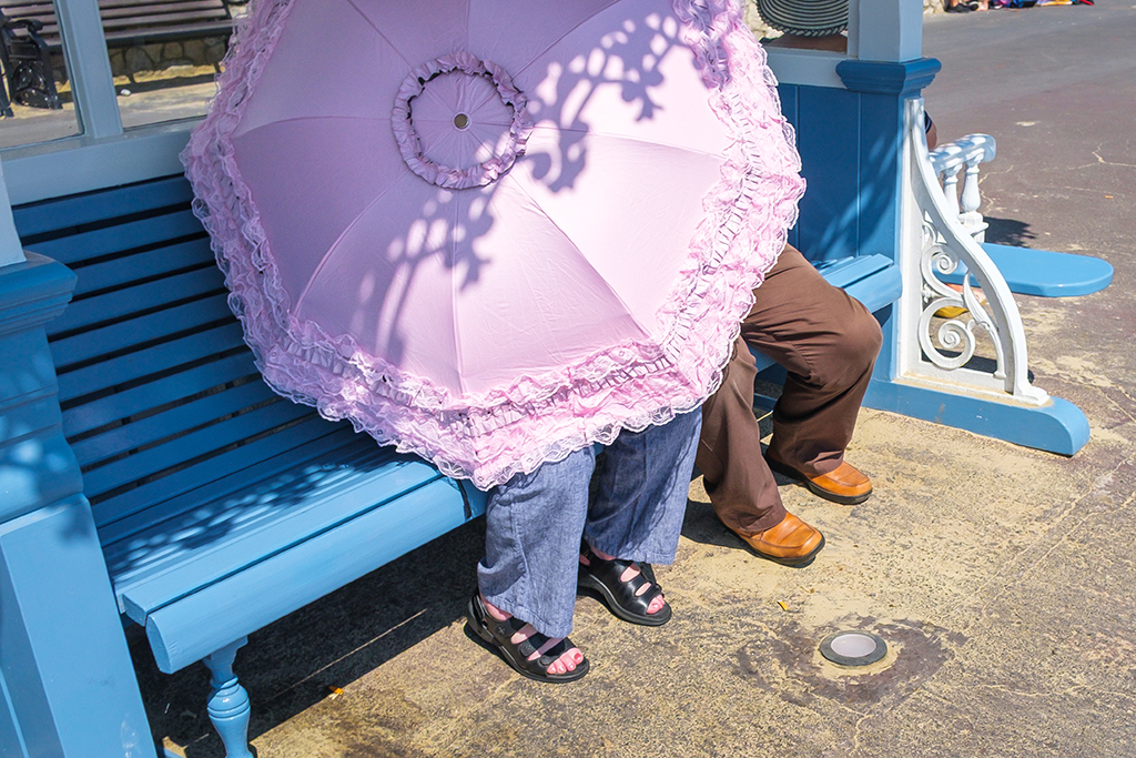 two people sat beneath a pink frilly umbrella