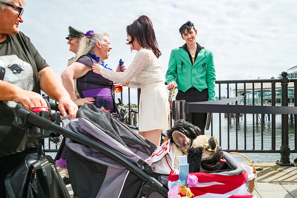 pug in elvis costume in a pram being walked past people