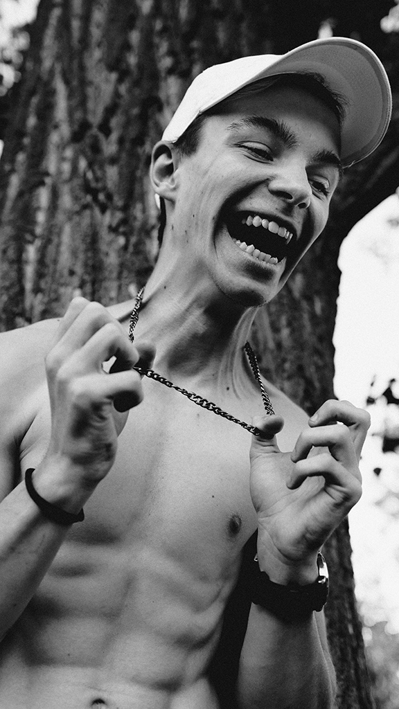 young man mid laugh holding chain