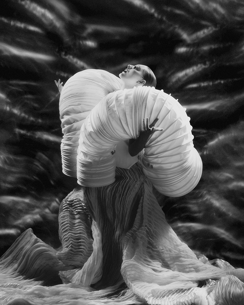 woman poses with dramatic dress with large shoulder piece for editorial shot