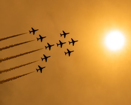 red arrows formation silhouette against orange sky