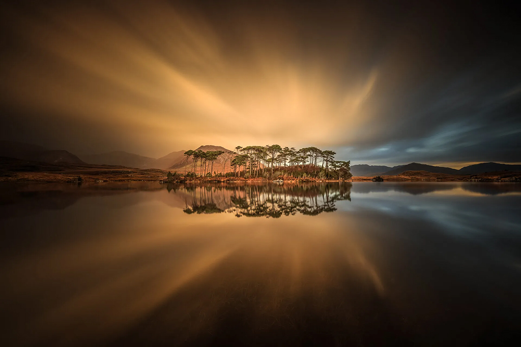 long exposure landscape photo of orange sky behind pine trees