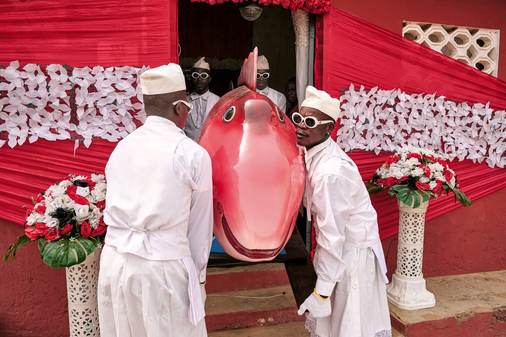 The eldest member of the family, a fishmonger, is honoured by her relatives with a fish coffin.
Nana Otafritsa takes care of the laying out and decoration of her room the evening before. On
Saturday, he and his Coffin Dancers dance with the coffin to his own music before carrying it
to the cemetery. Because the fish is too long for the prepared grave, the tail fin has to be sawn off.
Greater Accra, 2024. (Coffin: Eric Kpakpo). Image Credit: Regula Tschumi SINGLE USE ONLY