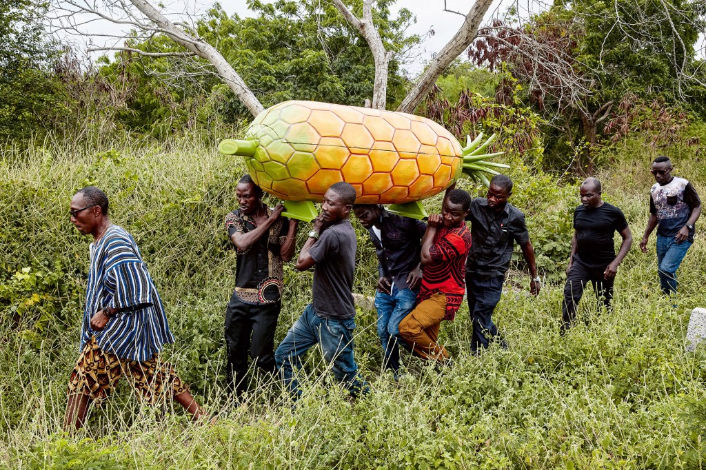 Relatives carry the coffin of a pineapple seller to her grave. Greater Accra, 2019. (Coffin: Eric
Kpakpo). Image Credit: Regula Tschumi SINGLE USE ONLY