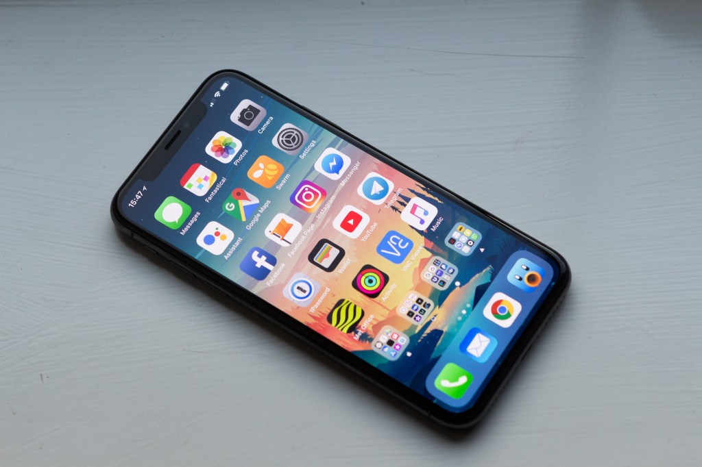 Photograph of iPhone X showing all-screen design, home screen and apps. 