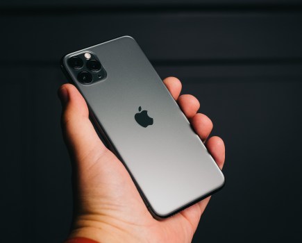 iPhoen 1 Pro Max photographed held by hand against dark background