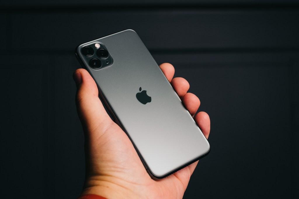 iPhoen 1 Pro Max photographed held by hand against dark background