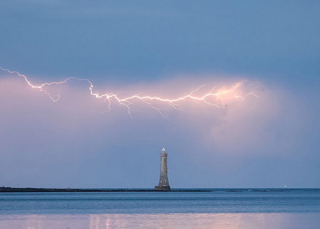 lightning over a lighthouse at sea