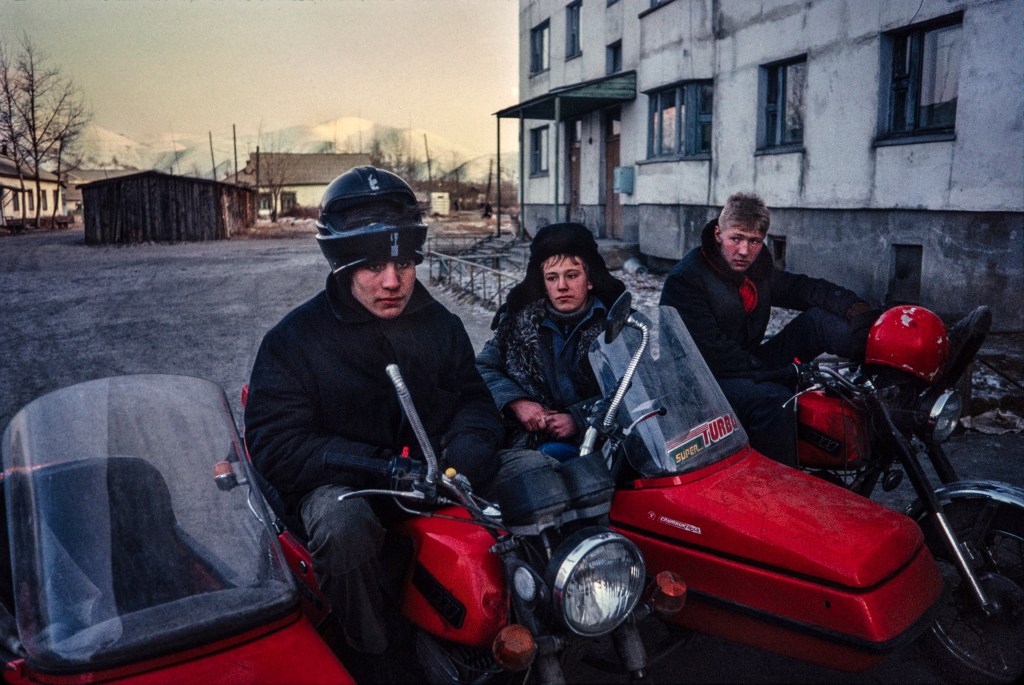Young men hanging out on their Jupiter motorbikes and sidecars below 10°C in the mining town of Ust-Omchug. Image Credit: Barry Lewis SINGLE USE ONLY