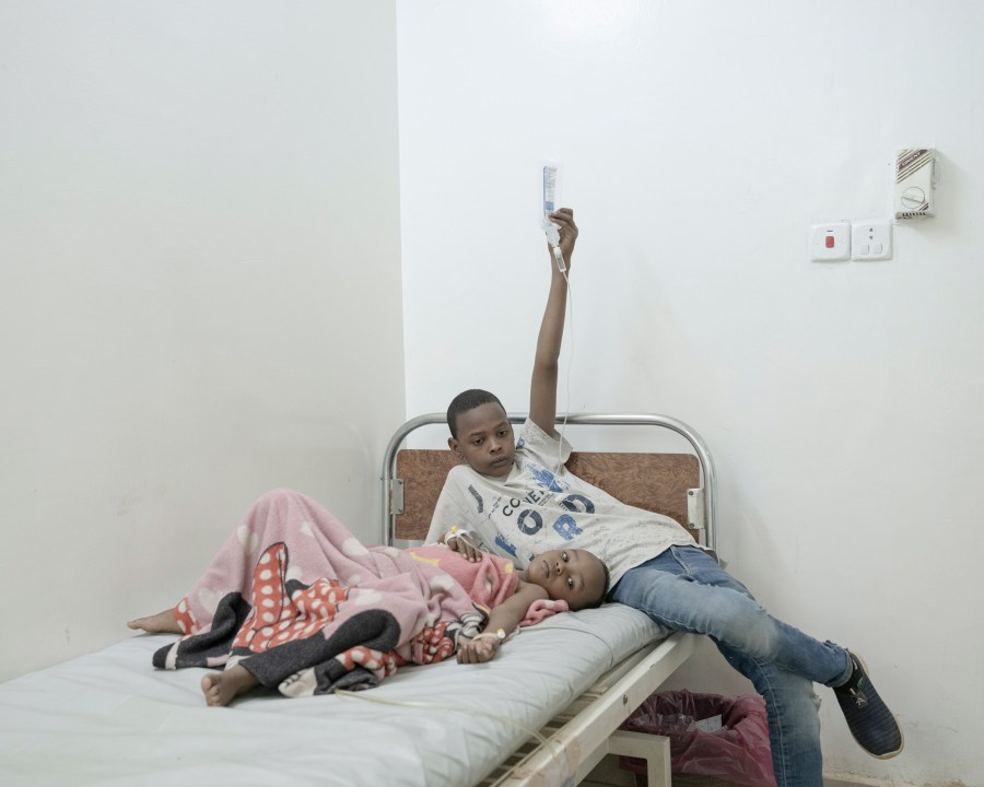 Noor (5), injured by gunfire months ago, awaits surgery while his brother Ahmed (14) holds the IV. Al Naw Hospital, Omdurman, Sudan, 2024. Image Credit: Johanna-Maria Fritz SINGLE USE ONLY